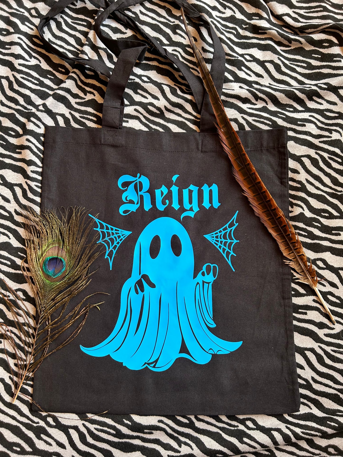 A tote bag, black with a print of a ghost, in blue with a name. This is an example of a customisation.