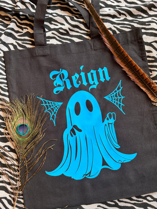 A tote bag, black with a print of a ghost, in blue with a name. This is an example of a customisation.
